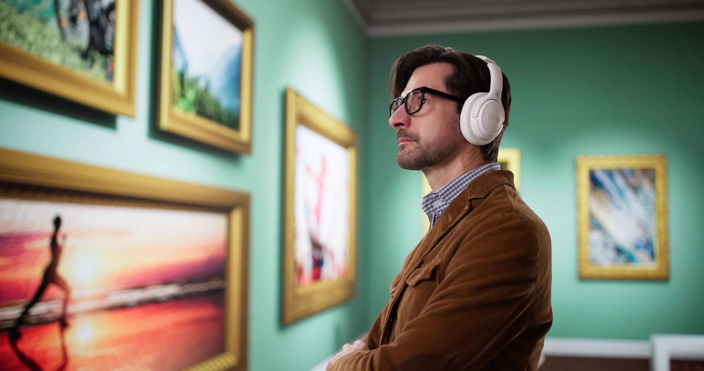 young man walks through a museum gallery, listening with headphones Engaging Audio guide narrations